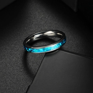 Polished titanium steel ring with blue faux opal inlay on dark matte stand