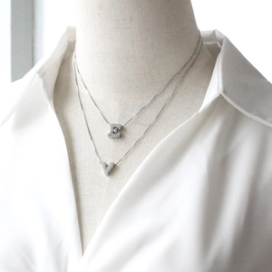 Detail of silver layering necklaces with zircon C and V initial pendants on a model