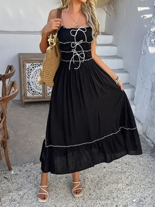 Detail of high waist black dress with white bow accents and pleated bodice design