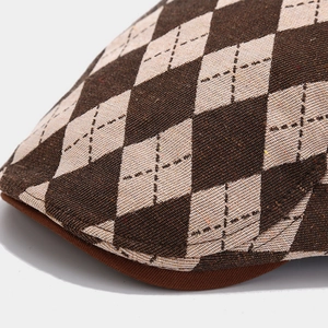 Close-up of diamond pattern fabric and stitching detail on a vintage brown newsboy cap