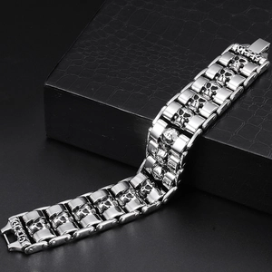 Macro shot of silver skull relief on punk steel bracelet resting on black leather texture