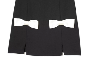 Detalle del dobladillo de un mini vestido negro con lazos de satén blanco y aberturas