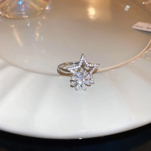 Detailed view of a silver spinning snowflake ring with zircons on a white ceramic plate