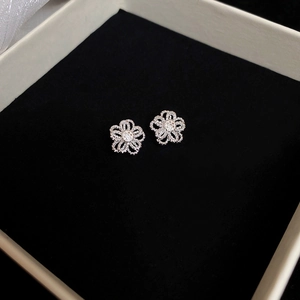Detail of silver hollow flower stud earrings displayed on black velvet gift box padding