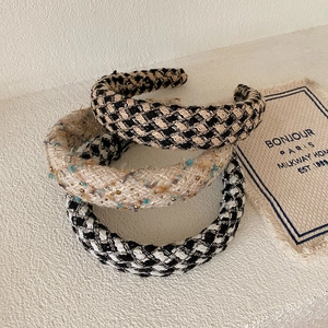 Close-up of three knitted plaid headbands in beige and black tweed with metallic thread