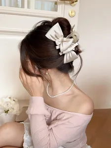 Detail of elegant champagne silk bow hair claw clip worn on a woman's hair