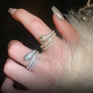 Gold and silver snake rings with zircon stones and green eyes on a model's hand
