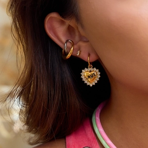 Gold heart drop earring with LOVE engraving and crystal border on female model ear