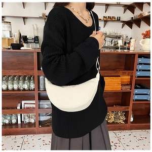 Lifestyle shot of a white corduroy dumpling bag worn with a casual autumn outfit