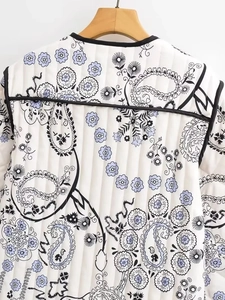 Detail of white quilted jacket with black and lilac paisley floral print and piping