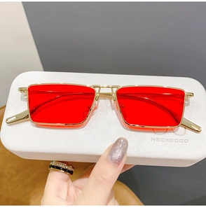 Detail of red lenses and gold metal square sunglasses with white textured hard case