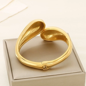 Detail of gold teardrop cuff bracelet with spring hinge on a jewelry display