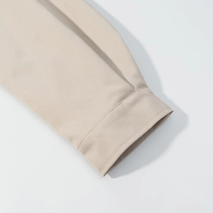 Close-up of beige jacket sleeve cuff showing fabric texture and neat stitching details