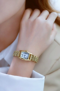 Detail view of a gold rectangular ladies watch featuring a Roman numeral dial and date window