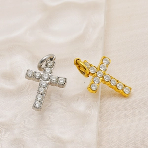 Détail macro de pendentifs en forme de croix dorés et argentés avec strass sur tissu en soie
