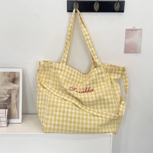 Detail view of yellow gingham tote bag featuring red Soxakka embroidery and canvas strap