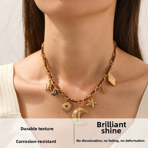 Dettaglio di collana boho dorata con ciondoli a forma di luna, stella marina e tartaruga