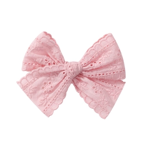 Close-up of pink lace bow hair clip featuring intricate eyelet embroidery and scalloped edges