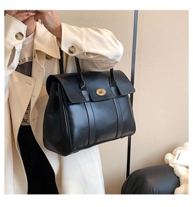 Close-up of black leather tote bag featuring a gold twist lock and fine stitching detail