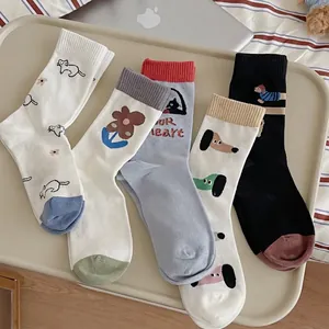 Five pack of cartoon crew socks with dog and flower patterns on a tray