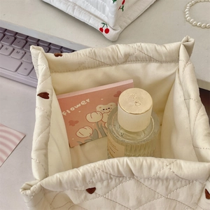 Detalle de una cesta de almacenamiento acolchada crema con corazones marrones bordados