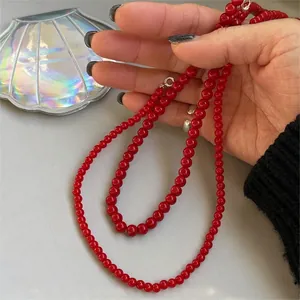 Close-up detail of a minimalist red beaded necklace with 925 silver clasp held by hand