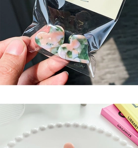 Gros plan de mini pinces à cheveux cœur en acétate marbré rose et vert sur un plateau