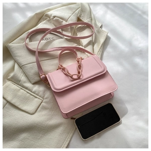 Pink PU leather crossbody bag with resin chain detail on white blazer background