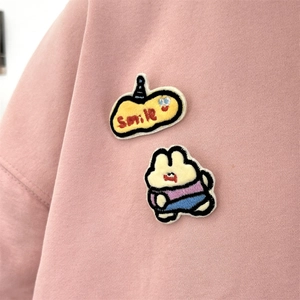 Close-up of smile embroidery and cute bunny patch on pink cotton sweatshirt fabric