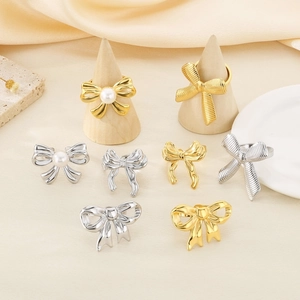 Close-up of gold and silver bow rings with pearls on elegant silk and stone display