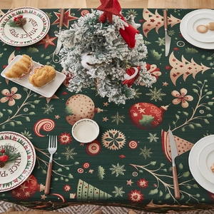 Close-up of dark green Christmas tablecloth with festive tree and snowflake patterns