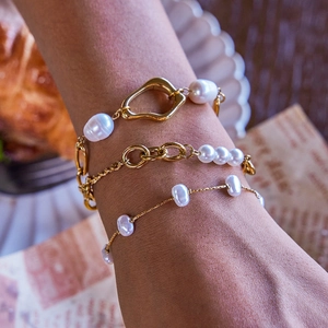 Macro detail of gold-plated butterfly bow bracelet with baroque pearls and lava metal texture