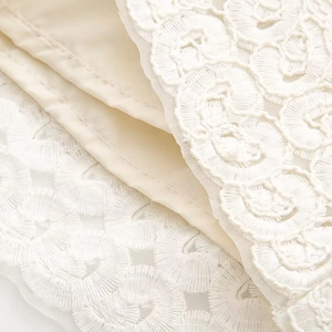 Close-up of white floral lace embroidery with high-quality beige satin lining fabric