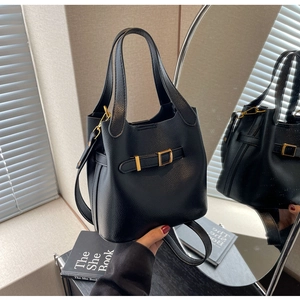 Detail of black lychee grain leather bucket bag with gold buckles and dual handles
