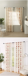 Close-up of beige lace curtains with red floral embroidery and delicate wavy edges