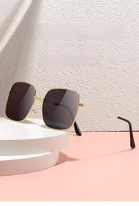 Detail view of oversized square gold metal sunglasses with dark gray lenses and slim temples