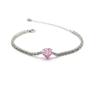 Détail d'un cristal rose en forme de cœur sur un bracelet tennis argenté serti de zircons