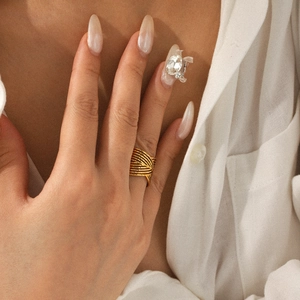 Dettaglio dell'anello bohémien dorato a linee incrociate indossato da una modella