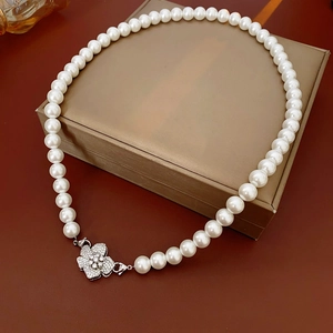 Close-up of white round pearl necklace with zircon flower buckle on vintage box