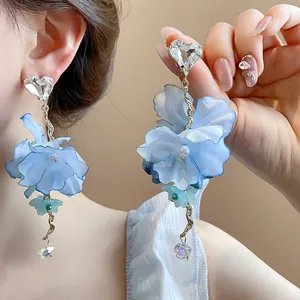 Dettaglio orecchini a fiore in tessuto blu con cuore di cristallo e catena dorata