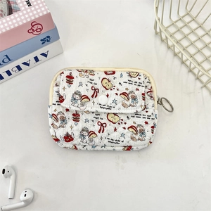 Flat lay of a white quilted cartoon coin purse with cat prints and a metal zipper hook