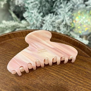 Pink marble acetate hair claw with gold Barrette La France text on a wooden tray