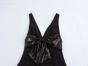 Dettaglio di un abito nero senza maniche con un grande fiocco di paillettes per feste