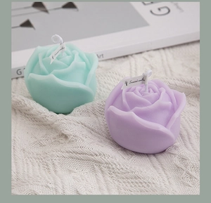 Detail of rose-shaped scented candles in mint green and light purple with cotton wicks
