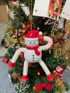Close-up of telescopic snowman pop tube toy with red suction cups hanging on a Christmas tree