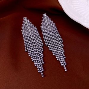 Close-up of purple rhinestone hollow teardrop tassel earrings on a textured fabric