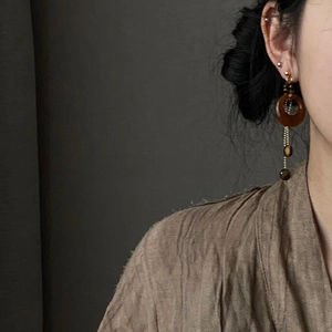 Detail of amber resin tiger eye drop earrings worn by a model in soft lighting