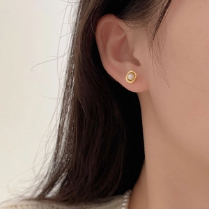 Gros plan d'un mannequin portant des boucles d'oreilles perles avec bordure dorée