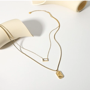 Detail of layered gold necklace featuring rectangular zircon and sun moon embossed charm