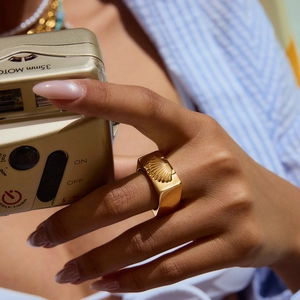 Gros plan d'une bague vintage en or 18 carats avec relief de coquillage sur l'index